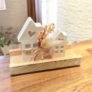 2 H&auml;user mit Blumendeko auf einem Holzbrett